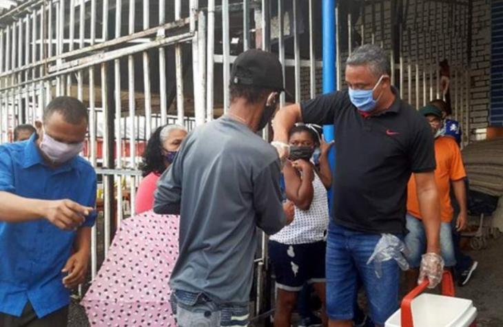 Voluntários servem água e comida de graça a pessoas na fila da Caixa
